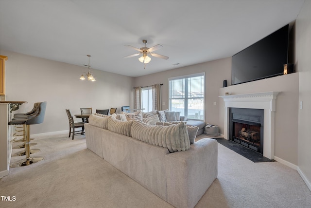 living room with ceiling fan with notable chandelier and light colored carpet