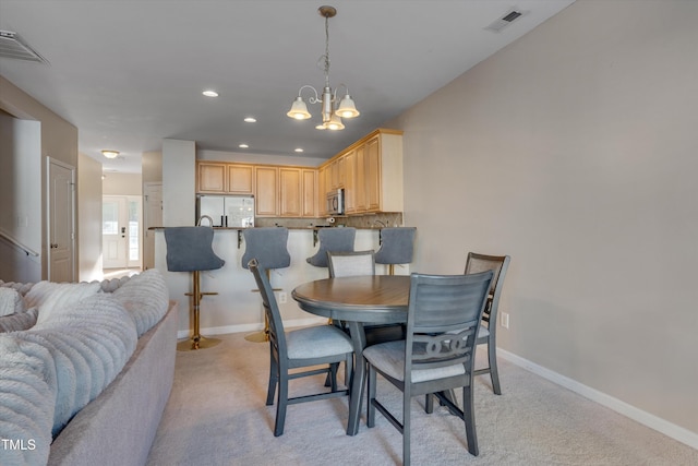 carpeted dining area featuring an inviting chandelier