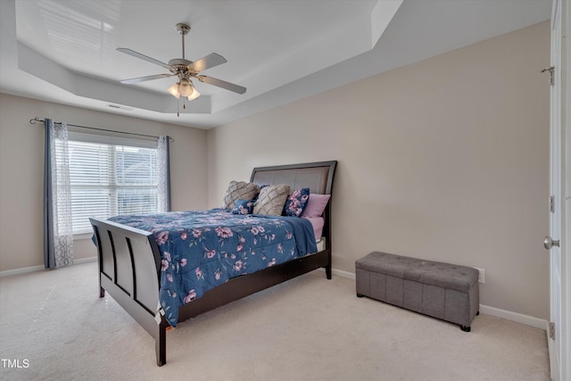 carpeted bedroom featuring a tray ceiling and ceiling fan