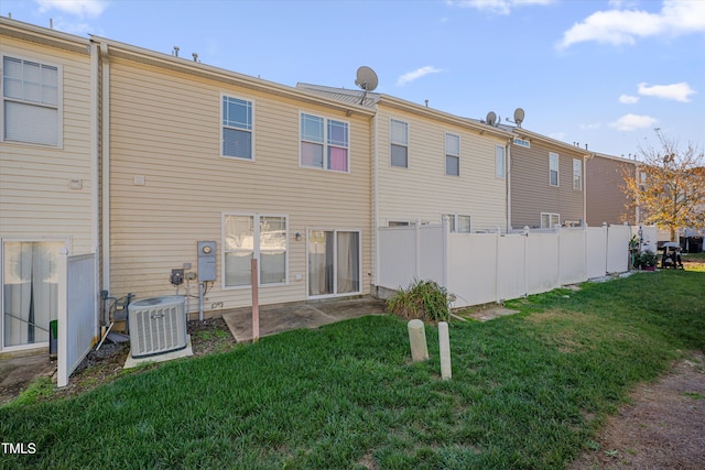 rear view of house with central air condition unit and a lawn