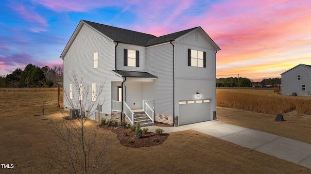 traditional home with central air condition unit, concrete driveway, and a garage