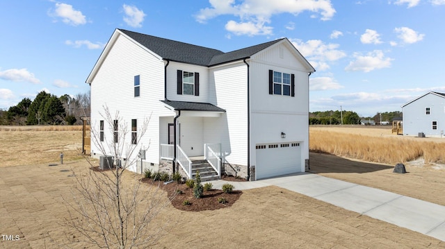 view of front of house featuring a garage, driveway, a shingled roof, and central AC unit