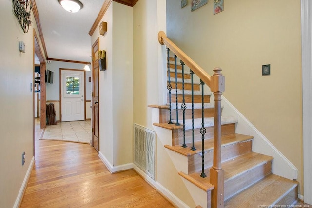 stairway with hardwood / wood-style floors and crown molding