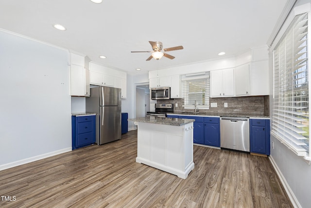 kitchen with white cabinets, blue cabinets, wood-type flooring, stainless steel appliances, and a center island