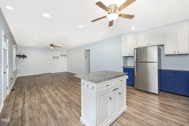 kitchen with blue cabinets, stainless steel fridge, white cabinetry, and a center island