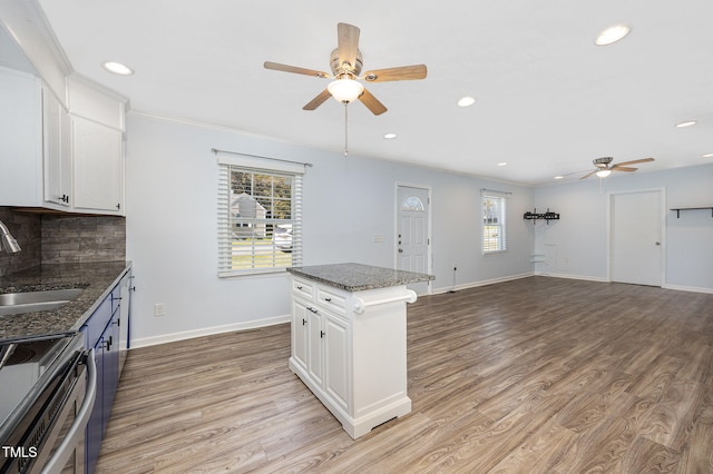 kitchen featuring backsplash, white cabinetry, sink, light hardwood / wood-style floors, and a center island