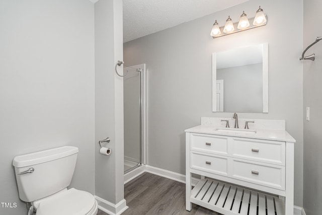 bathroom featuring hardwood / wood-style floors, an enclosed shower, a textured ceiling, toilet, and vanity