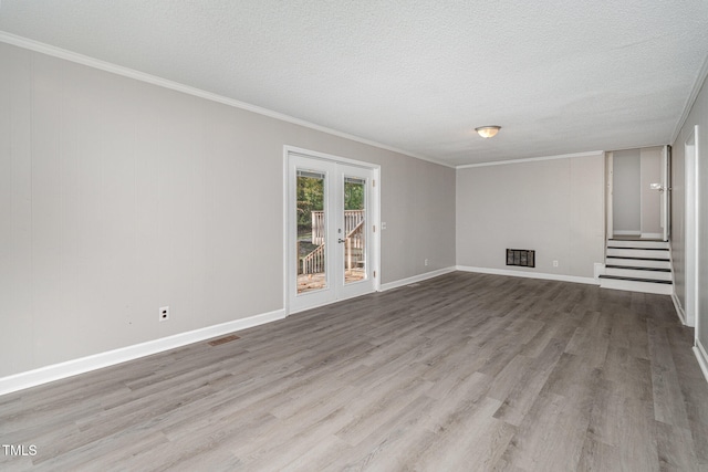 empty room featuring light hardwood / wood-style floors, ornamental molding, a textured ceiling, and french doors