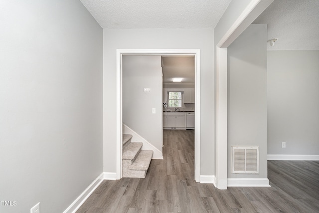 hall featuring a textured ceiling and hardwood / wood-style flooring