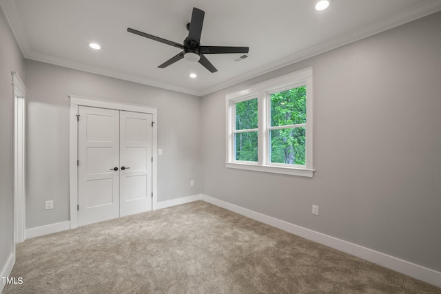 unfurnished bedroom with carpet, a closet, ceiling fan, and crown molding