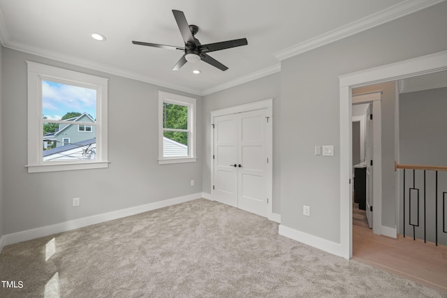 unfurnished bedroom featuring a closet, ceiling fan, ornamental molding, and light colored carpet