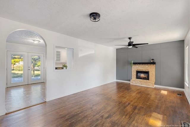 unfurnished living room with french doors, hardwood / wood-style floors, a textured ceiling, and ceiling fan