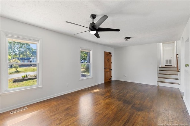 empty room featuring a textured ceiling, dark wood-type flooring, and plenty of natural light