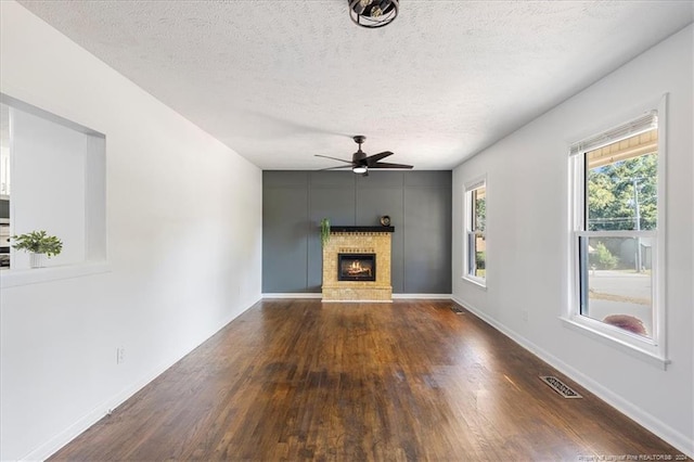 unfurnished living room featuring hardwood / wood-style floors, a textured ceiling, a fireplace, and ceiling fan