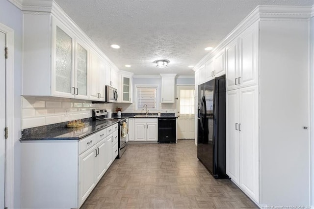 kitchen featuring black appliances, sink, parquet flooring, white cabinets, and decorative backsplash