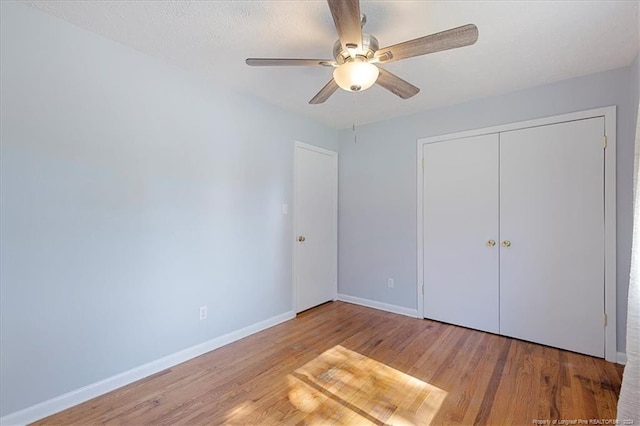 unfurnished bedroom with a closet, a textured ceiling, wood-type flooring, and ceiling fan