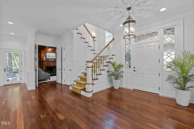 entrance foyer featuring dark wood-type flooring, crown molding, and a notable chandelier