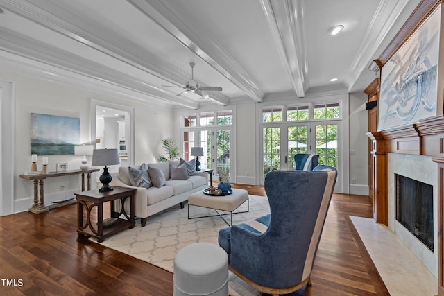 living room featuring beam ceiling, dark wood-type flooring, a premium fireplace, ornamental molding, and ceiling fan