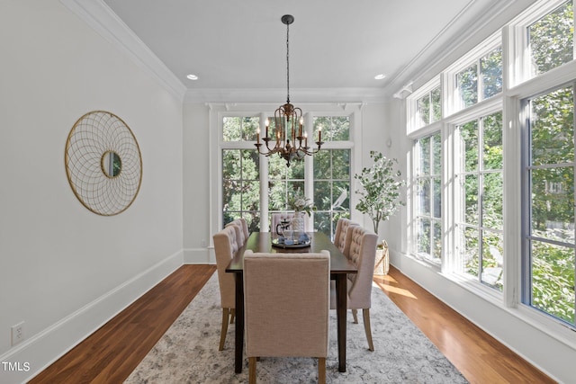 dining area featuring an inviting chandelier, crown molding, hardwood / wood-style flooring, and a wealth of natural light