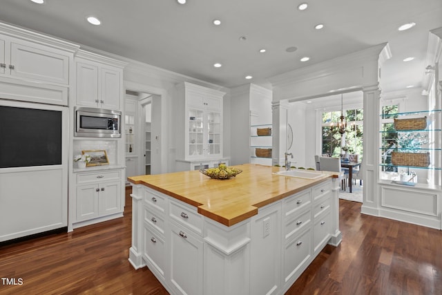 kitchen featuring dark hardwood / wood-style flooring, stainless steel microwave, white cabinetry, wooden counters, and sink