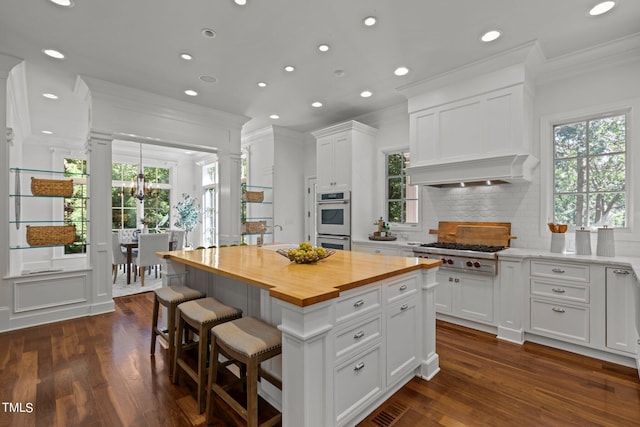 kitchen featuring butcher block countertops, appliances with stainless steel finishes, a center island, and white cabinetry