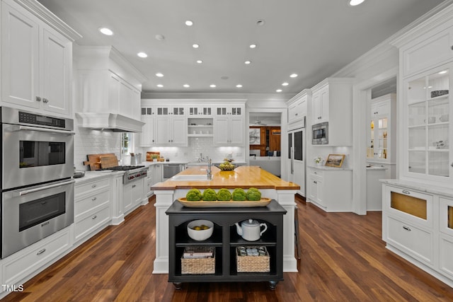 kitchen featuring built in appliances, dark wood-type flooring, and white cabinets