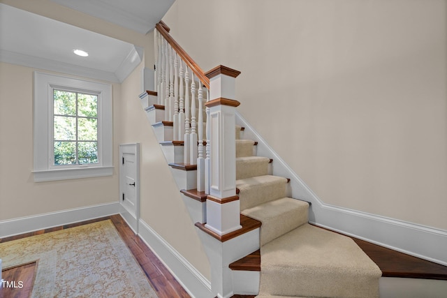 stairway featuring crown molding and hardwood / wood-style flooring