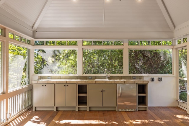 unfurnished sunroom featuring vaulted ceiling with beams and sink