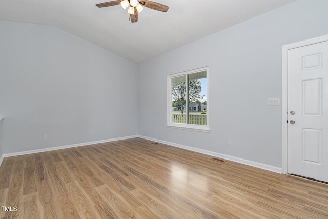 spare room featuring lofted ceiling, a textured ceiling, light hardwood / wood-style floors, and ceiling fan