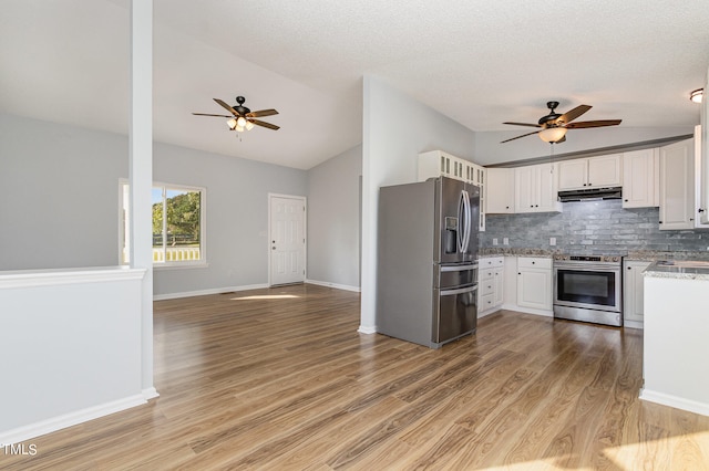 kitchen with lofted ceiling, appliances with stainless steel finishes, light hardwood / wood-style floors, and white cabinets