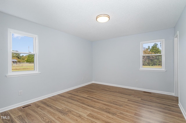 unfurnished room featuring wood-type flooring and a textured ceiling