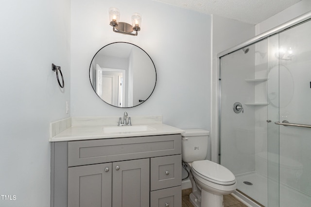 bathroom with vanity, toilet, walk in shower, and a textured ceiling