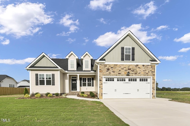craftsman house featuring fence, stone siding, driveway, a front yard, and board and batten siding
