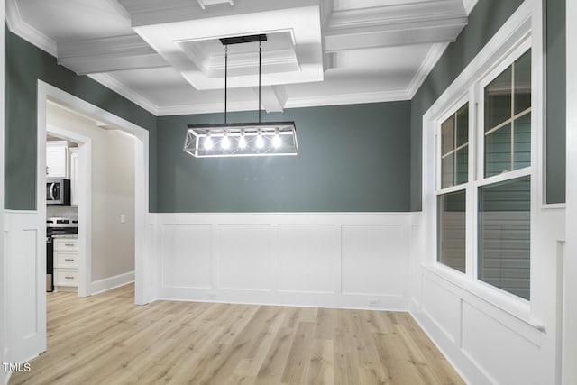 unfurnished dining area with wainscoting, crown molding, a decorative wall, and light wood-style floors