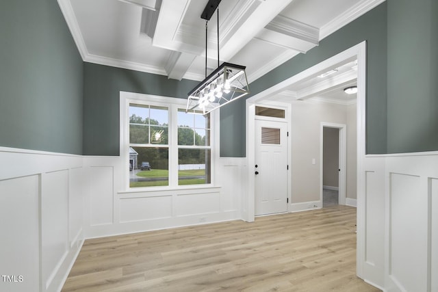 unfurnished dining area with light wood finished floors, an inviting chandelier, a decorative wall, crown molding, and a wainscoted wall