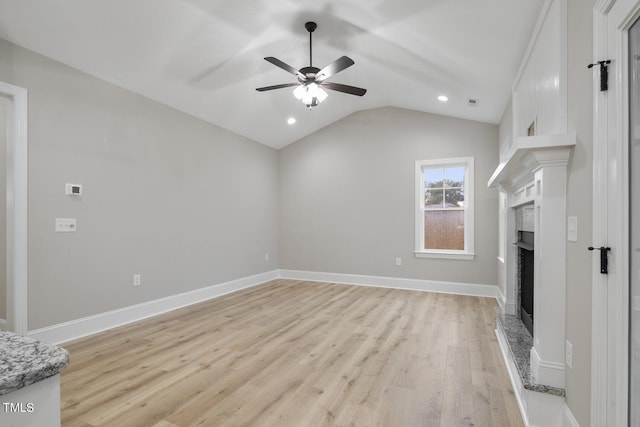 unfurnished living room with lofted ceiling, light wood-type flooring, a fireplace with raised hearth, recessed lighting, and a ceiling fan
