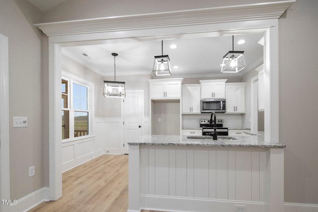 kitchen featuring stainless steel appliances, sink, light stone countertops, decorative light fixtures, and white cabinetry