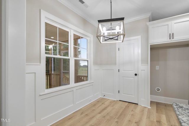 unfurnished dining area featuring light hardwood / wood-style floors, ornamental molding, and a chandelier