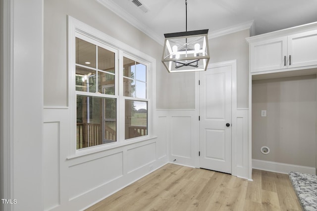 unfurnished dining area featuring an inviting chandelier, visible vents, a decorative wall, light wood-style floors, and ornamental molding