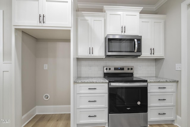 kitchen featuring white cabinetry, light wood finished floors, stainless steel appliances, and decorative backsplash