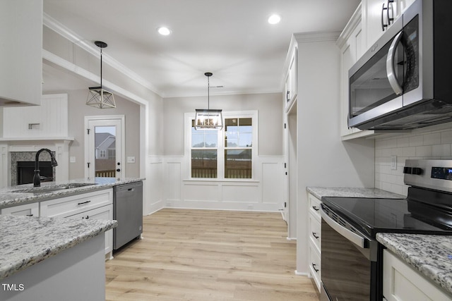 kitchen featuring a sink, a fireplace, pendant lighting, white cabinets, and appliances with stainless steel finishes