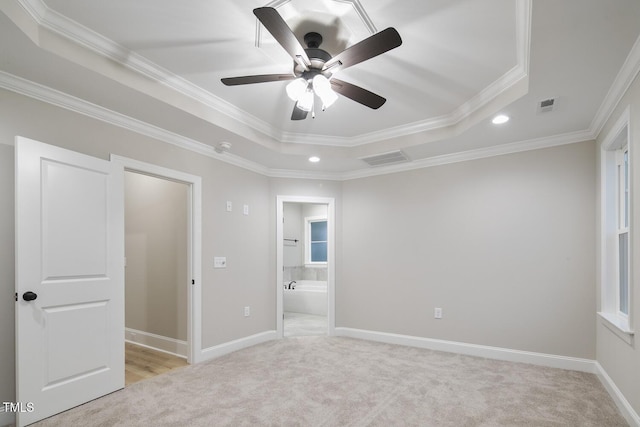 unfurnished bedroom with ornamental molding, a raised ceiling, light carpet, and visible vents