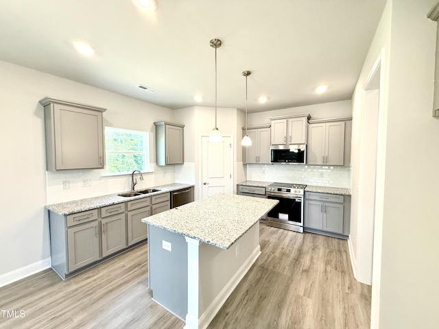 kitchen featuring gray cabinets, visible vents, appliances with stainless steel finishes, a sink, and light wood finished floors