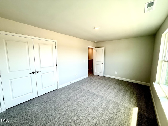 unfurnished bedroom featuring baseboards, carpet, a closet, and visible vents