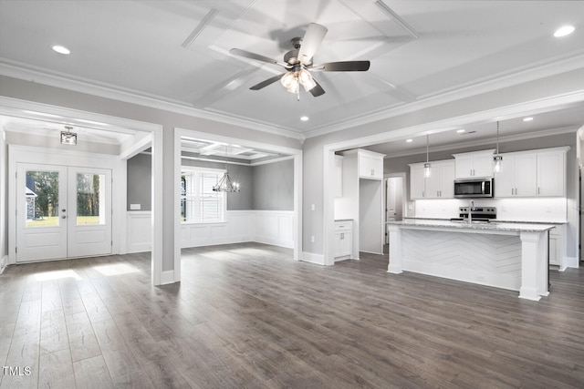 unfurnished living room with dark wood-type flooring, ceiling fan with notable chandelier, french doors, and crown molding