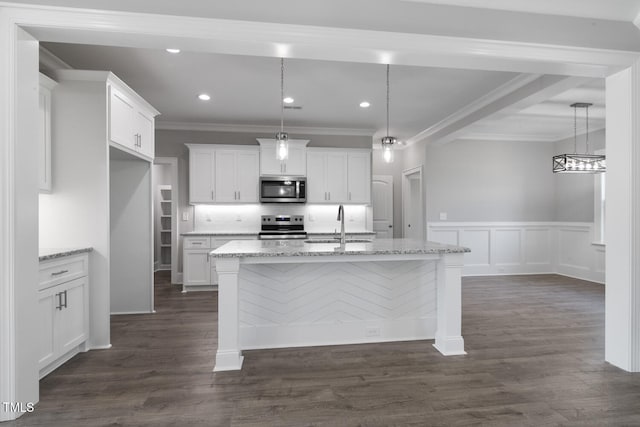 kitchen featuring light stone counters, a kitchen island with sink, and appliances with stainless steel finishes