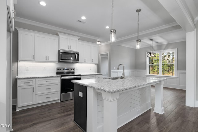 kitchen featuring stainless steel appliances, sink, hanging light fixtures, an island with sink, and white cabinets