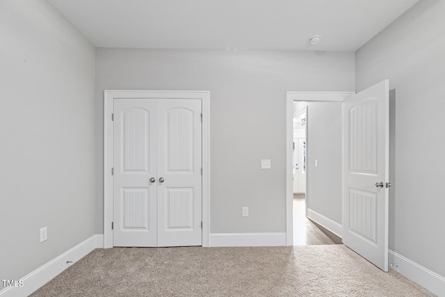 unfurnished bedroom with a closet and light colored carpet