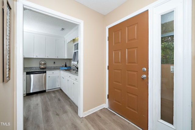 kitchen featuring stainless steel dishwasher, a textured ceiling, light hardwood / wood-style floors, white cabinets, and sink