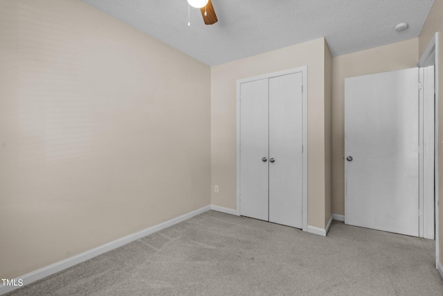 unfurnished bedroom featuring a closet, ceiling fan, a textured ceiling, and light colored carpet